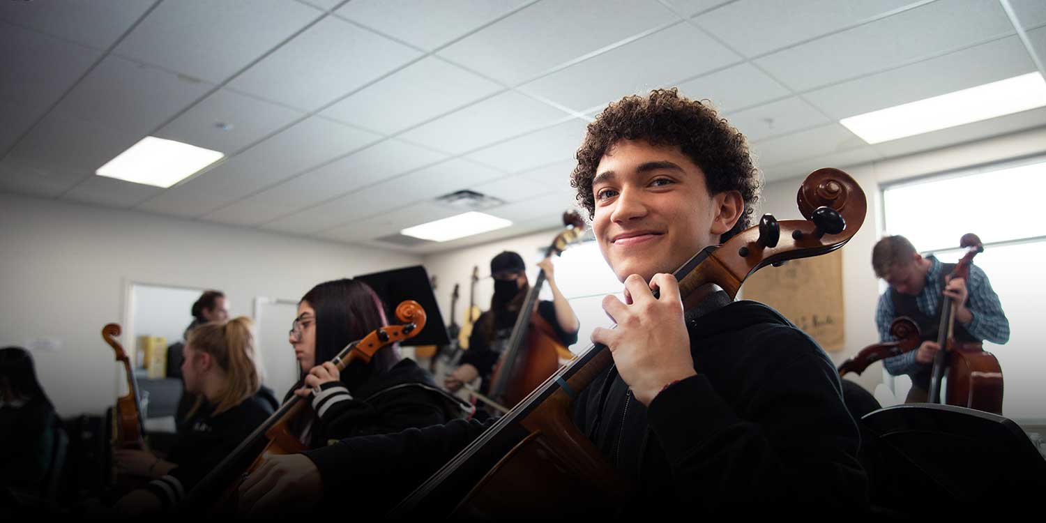 Smiling student in the classroom playing an instrument